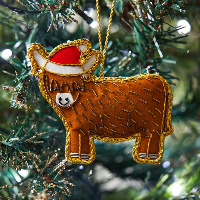 Highland Cow Hanging Decoration with a red hat hanging on a Christmas tree.
